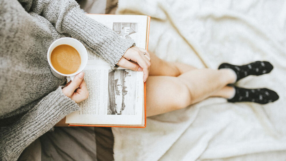 Девушка с чашкой кофе читает книгу